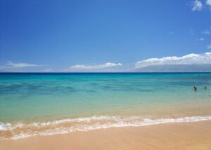 Two vacationers wade near the shoreline of a beautiful Maui beach.