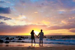 Couple holding hands at the beach at sunset: things to do in Maui for couples